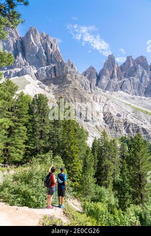 Rückansicht von zwei jungen Wanderern, die die Geisler vom berühmten Adolf-Munkel-Weg aus bewundern, Val di Funes, Südtirol, Dolomiten, Italien, Europa Stockfoto