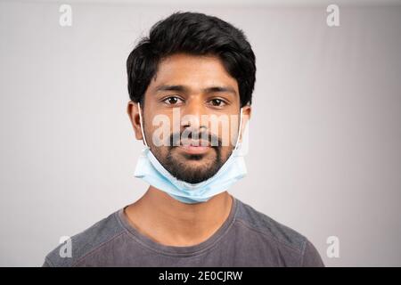 Junger Mann trägt medizinische Maske auf Hals- Konzept zeigt die unsachgemäße Art und Weise der Verwendung von Gesichtsmasken während Coronavirus oder covid-19 Krise. Stockfoto