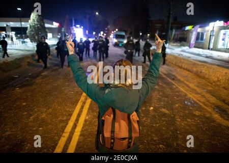 Minneapolis, Minnesota, USA. Dezember 2020. Eine Frau gibt der Polizei 2 Mittelfinger, als sie sich von den Protestierenden zurückkehrt und den Bereich verließ, in dem ein Offizier am Tag zuvor jemanden erschossen hat. Die Szene der Dreharbeiten war eine Meile entfernt von, wo George Floyd durch den ehemaligen Offizier Derek Chauvin im Mai getötet wurde. Quelle: Chris Juhn/ZUMA Wire/Alamy Live News Stockfoto