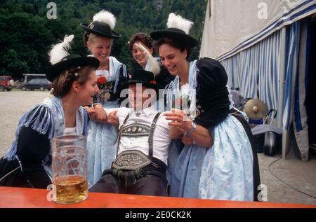 Deutschland /Bayern /Frau hilft einem betrunkenen Mann in traditioneller bayerischer Kleidung beim örtlichen Bierfest. Stockfoto