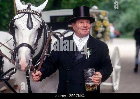 Deutschland /Bayern /München /der Mann in elegantem Zylinder hält dagegen ein Pferd und ein großes Glas Bier in der Hand. Stockfoto