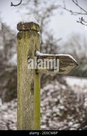 Schneebedeckter Wegweiser auf dem Wanderweg, der im Winter Anweisungen gibt Stockfoto