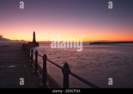 Sonnenaufgang am Roker Pier und Leuchtturm, der von der Nordseeküste bei Sunderland, Tyne und Wear, Nordostengland, reicht. Stockfoto