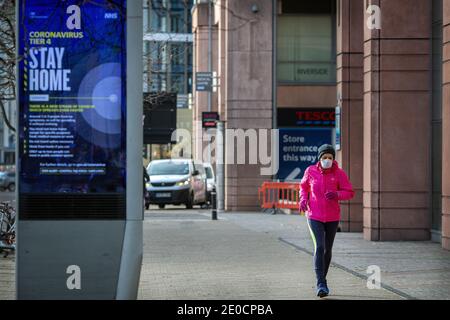 Eine Frau mit Gesichtsmaske läuft an einem 'Stay Home' vorbei Coronavirus-Zeichen in Vauxhall.London wurde unter Tier 4 platziert Einschränkungen wie Fälle zu steigen und ne Stockfoto