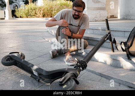 Junger Mann Unfall Mit Einem Elektroroller Auf Der Straße. Ein Mann fiel von einem Roller auf einer Stadtstraße. Stockfoto