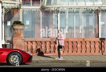 Brighton UK 31. Dezember 2020 - Es ist Kurzwetter für diesen Kerl warten auf ein Taxi, wie er das sonnige, aber kalte Wetter entlang Brighton Küste am Silvester genießt . Kredit Simon Dack / Alamy Live Nachrichten Stockfoto