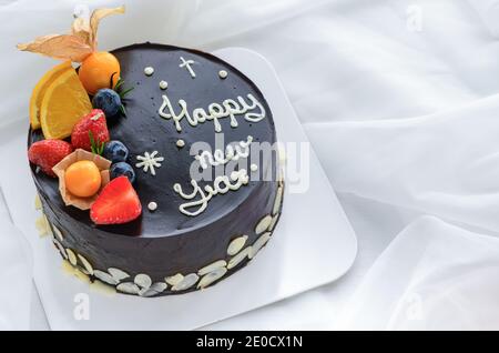 Schokoladenkuchen mit Orange, Erdbeere, Heidelbeere und Cape Gooseberry auf weißem Stoffhintergrund, Kopierraum und Dessertkonzept Stockfoto