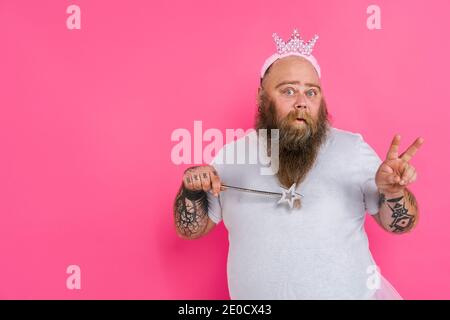 Lustige fette Mann vorgibt, eine Ballerina mit Tutu zu sein - Comic-Charakter mit Bart und Tätowierungen tanzen auf einem Rosa Hintergrund Stockfoto