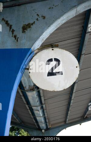 Zwei und Sekunde - Zahl, Zahl, Zahl und numerales Zeichen. Schild auf der Plattform. Detail und Nahaufnahme des alten und baufälligen Gebäudes aus Beton Stockfoto