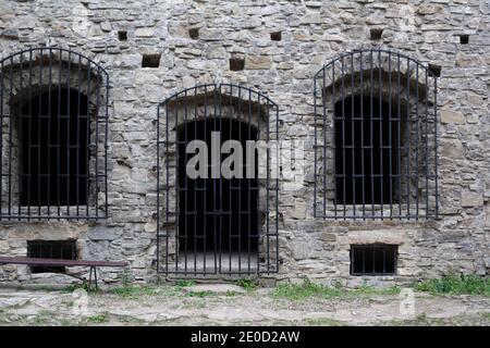 Historisches Gefängnis, Gefängnis und Gefängnis - alte, historische und antike Mauer aus Stein. Fenster und Türen mit Eisenstangen und Gitter. Stockfoto