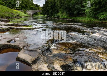 Stainforth Force auf dem River Ribble, mit der alten Packhorse-Brücke im Hintergrund, in der Nähe von Settle, Yorkshire Dales National Park, West Yorkshire Stockfoto