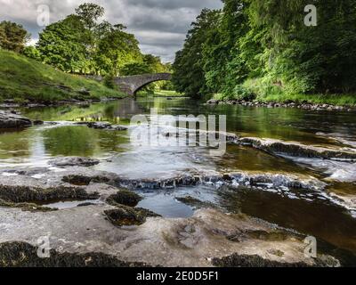 Stainforth Force auf dem River Ribble, mit der alten Packhorse-Brücke im Hintergrund, in der Nähe von Settle, Yorkshire Dales National Park, West Yorkshire Stockfoto