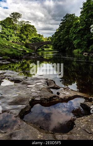 Stainforth Force auf dem River Ribble, mit der alten Packhorse-Brücke im Hintergrund, in der Nähe von Settle, Yorkshire Dales National Park, West Yorkshire Stockfoto