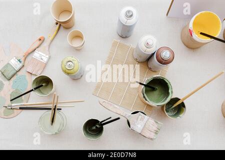 Draufsicht auf verschiedene Farben und Pinsel, die auf dem Tisch platziert sind In der kreativen Werkstatt Stockfoto