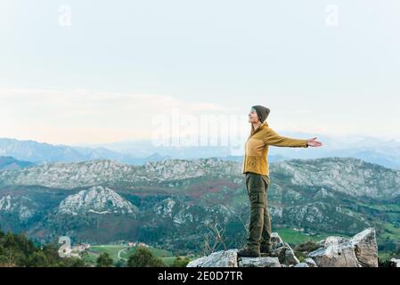 Seitenansicht des Entdeckers, der auf rauem Felsen steht und genießt Landschaft von Hochland während des Urlaubs Stockfoto