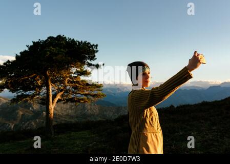 Seitenansicht der Abenteurerin auf einem Hügel im Hochland Und Foto von Tal und Meer bei Sonnenuntergang während Reisen Stockfoto