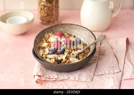 Eine Schüssel Müsli mit Nüssen und Hafer serviert mit Beeren und Milch Stockfoto