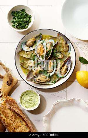 Gekochte Kiwi-Muscheln mit Wein, Knoblauch und Petersilie serviert mit Baguette und Butter mit Kräutern Stockfoto