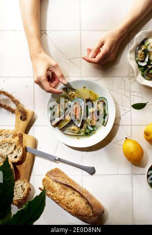 Gekochte Kiwi-Muscheln mit Wein, Knoblauch und Petersilie serviert mit Baguette und Butter mit Kräutern Stockfoto