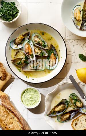 Gekochte Kiwi-Muscheln mit Wein, Knoblauch und Petersilie serviert mit Baguette und Butter mit Kräutern Stockfoto