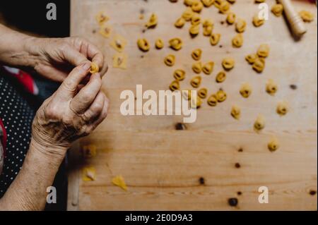 Von oben der Ernte unkenntlich Senior weibliche Küche schmackhaft traditionell Tortellini am Holztisch in der gemütlichen Küche Stockfoto