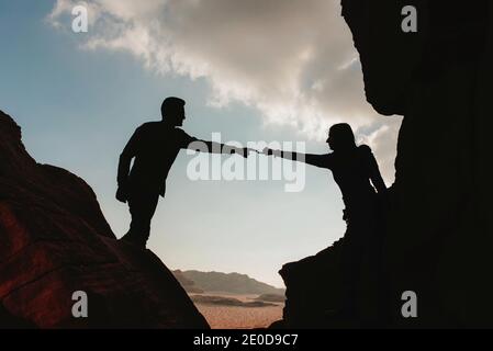 Seitenansicht der Silhouette eines anonymen Paares von Reisenden stehend Auf Felsen im Wadi Rum Sandsteintal und Hände berühren Während des Urlaubs in Jordanien Stockfoto