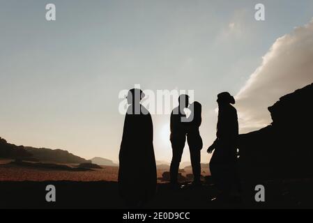 Seitenansicht der Silhouette eines anonymen Paares von Reisenden stehend Küssen auf felsigen Statue im Wadi Rum Sandstein Tal während Urlaub nach Jordanien Stockfoto