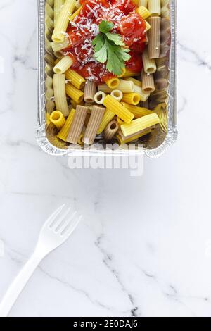 Von oben köstliche Makkaroni mit Ketchup und Käse platziert Im Behälter für Essen zum Mitnehmen auf Tisch mit Kunststoffgabel Stockfoto