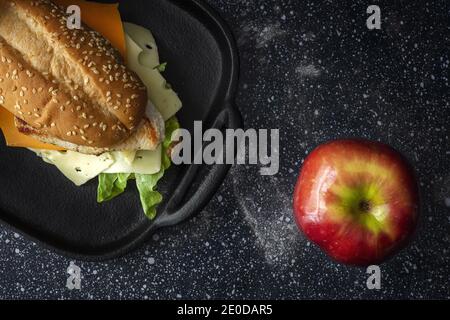 Von oben von köstlichen Sandwich mit Käse und Salat platziert Auf dem Tisch mit reifen Apfel Stockfoto