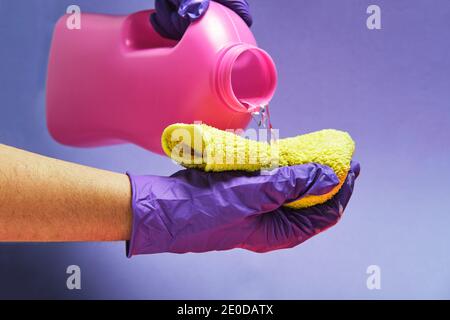 Crop anonyme Person mit Plastikflasche Gießen Flüssigwaschmittel in Ein Lappen im Studio Stockfoto