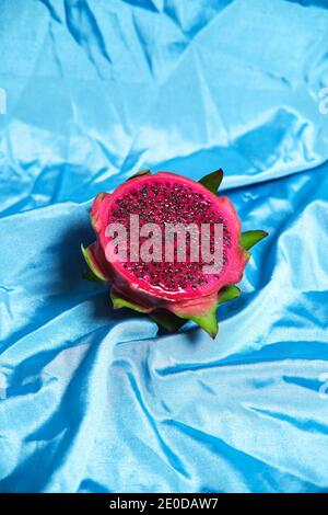 Hoher Winkel der Hälfte der köstlichen Pitaya Frucht auf gelegt Faltiges blaues Tuch im Studio Stockfoto