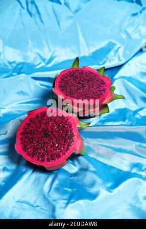 Der hohe Winkel der Hälften der köstlichen pitaya Frucht auf gelegt Faltiges blaues Tuch im Studio Stockfoto