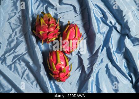 Von oben ganze frische Pitaya Früchte auf blau angeordnet Faltiges Tuch im Studio Stockfoto