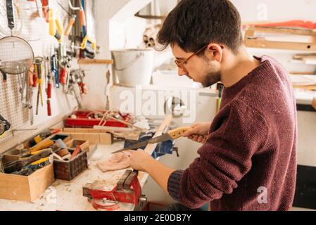 Seitenansicht hohe Winkel der beschäftigt männlichen Holzarbeiter mit scharfen Sägen und Schneiden von Holzbrett in der Werkstatt Stockfoto