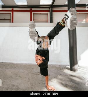 Voller Körper von energischen jungen Mann dabei akrobatische Handstand während Break Dance Stockfoto