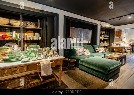 Stilvolles Innenraumdesign der Lounge- und Essbereiche in Zimmer mit Holzboden mit grünen weichen Sofa und eingerichtet Vintage Holztisch Einstellung mit Stockfoto