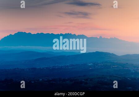 Spektakuläre Landschaft der Berge Silhouetten mit Häusern auf Pisten Gegen rosa Sonnenuntergang Himmel in der Landschaft in Kantabrien Stockfoto