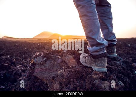 Rückansicht von unkenntlich weibliche Reisende in Casual Outfit stehen Auf unwegsamem felsigen Gelände und bewundern Sie die malerische Landschaft des Sonnenuntergangs Über die Berge Stockfoto