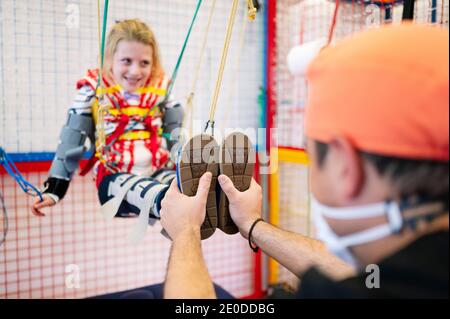 Crop anonyme Spezialist Unterstützung für Mädchen mit Angelman-Syndrom Während des Rehabilitationstrainings mit elastischen Bändern Stockfoto