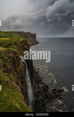 Erstaunliche abgelegene Luftaufnahme des Neist Point Lighthouse befindet sich auf Grüne Felsklippe vor dem ruhigen Meer auf sonnigen Tag in Schottland Stockfoto