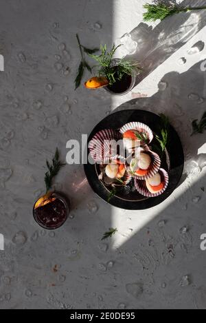 Blick von oben auf leckere orientalische Gericht aus Muscheln mit Kräuter auf dem Tisch serviert mit Gläsern erfrischender Cocktails garniert Mit getrockneten Orangen Stockfoto