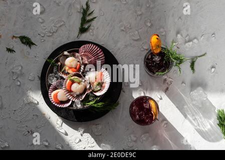 Blick von oben auf leckere orientalische Gericht aus Muscheln mit Kräuter auf dem Tisch serviert mit Gläsern erfrischender Cocktails garniert Mit getrockneten Orangen Stockfoto
