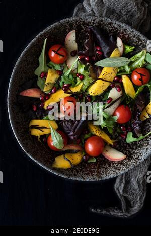 Draufsicht auf leckeren nährenden Salat mit verschiedenen reifen Zutaten Serviert in Schale auf schwarzem Hintergrund Stockfoto