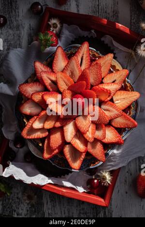 Von oben von süßen Tarte mit frischen Erdbeeren serviert dekoriert Auf Holztablett auf Tisch mit verschiedenen Beeren Stockfoto