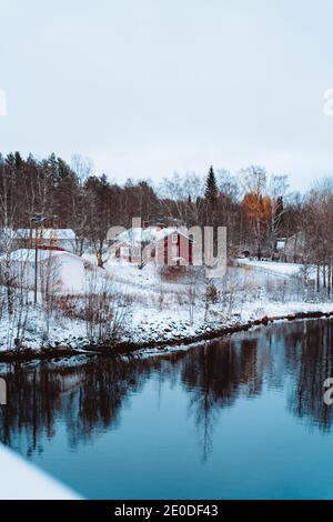 Winterlandschaft mit Wohn-Landhaus in der Nähe von ruhigen See Im Wald im Winter Stockfoto
