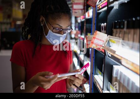 Afro latina junge Frau trägt eine Gesichtsmaske Shopping Make-up-Produkte Stockfoto