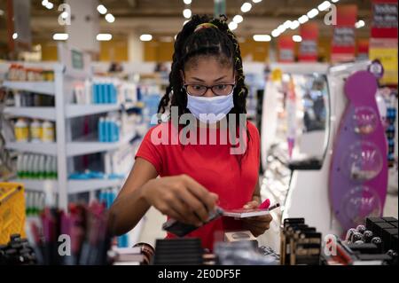 Afro latina junge Frau trägt eine Gesichtsmaske Shopping Make-up-Produkte Stockfoto