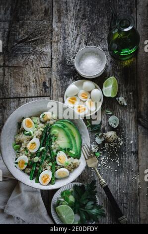 Von oben köstlicher gesunder Quinoa-Salat mit Avocado-Eiern Und Spargel auf Holztisch mit Zutaten Schüsseln in Küche Stockfoto