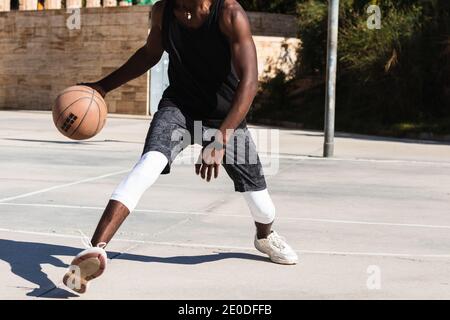 Cropped unkenntlich afroamerikanischen männlichen Athleten spielen Basketball auf dem Platz Im Sommer und Blick auf die Kamera Stockfoto