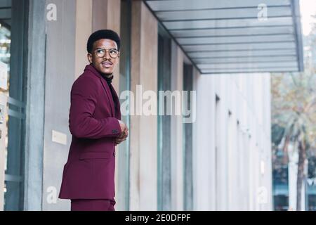 Fröhlicher junger afroamerikanischer Geschäftsmann in stilvollem Anzug und Brillen Zu Fuß auf der Straße Stockfoto